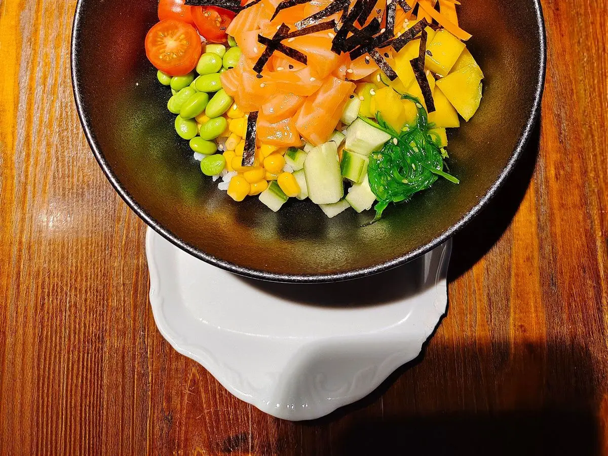 Cuenco de poke con salmón, aguacate, edamame, tomate cherry, zanahoria y tiras de alga nori