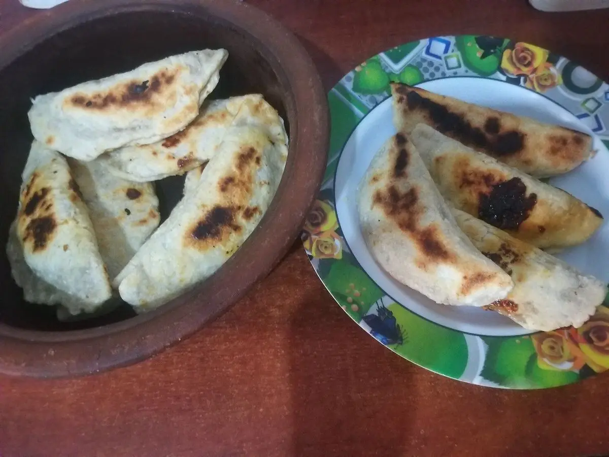 Roti de coco de Sri Lanka, tortas planas doradas con manchas de tostado, en un cuenco de barro y un plato