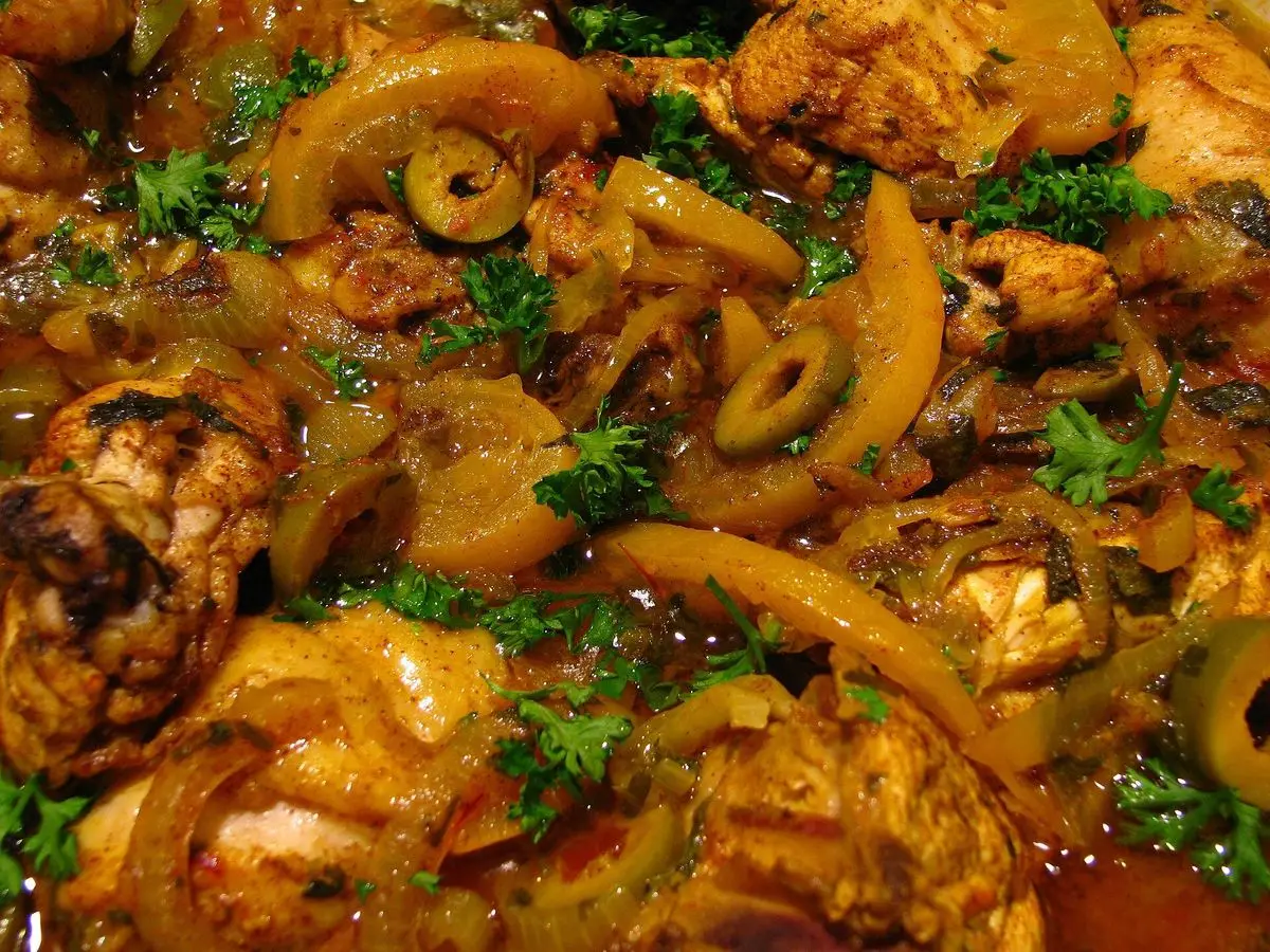 Pollo guisado con aceitunas, cebolla y hierbas en una cazuela