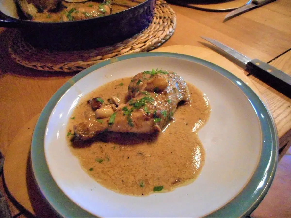 Plato con pollo salteado en salsa cremosa de vino blanco con ajos, sobre una mesa de madera