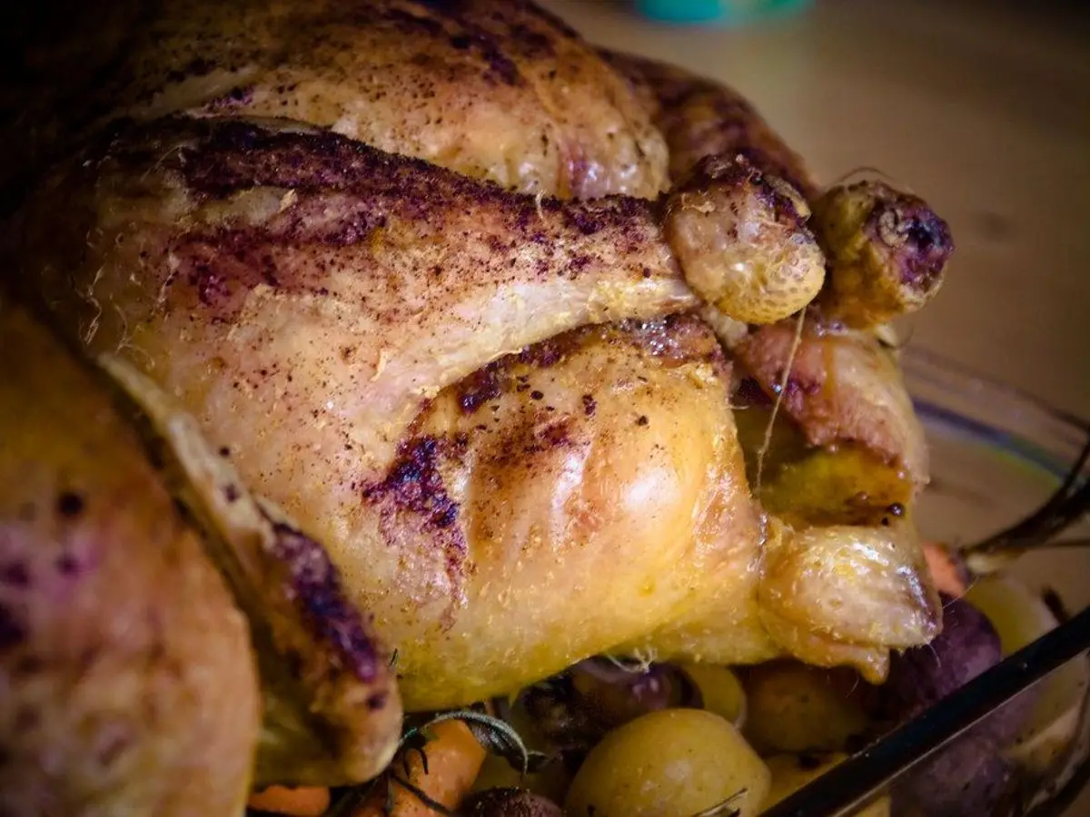Pollo entero asado dorado con patatas en la fuente de horno