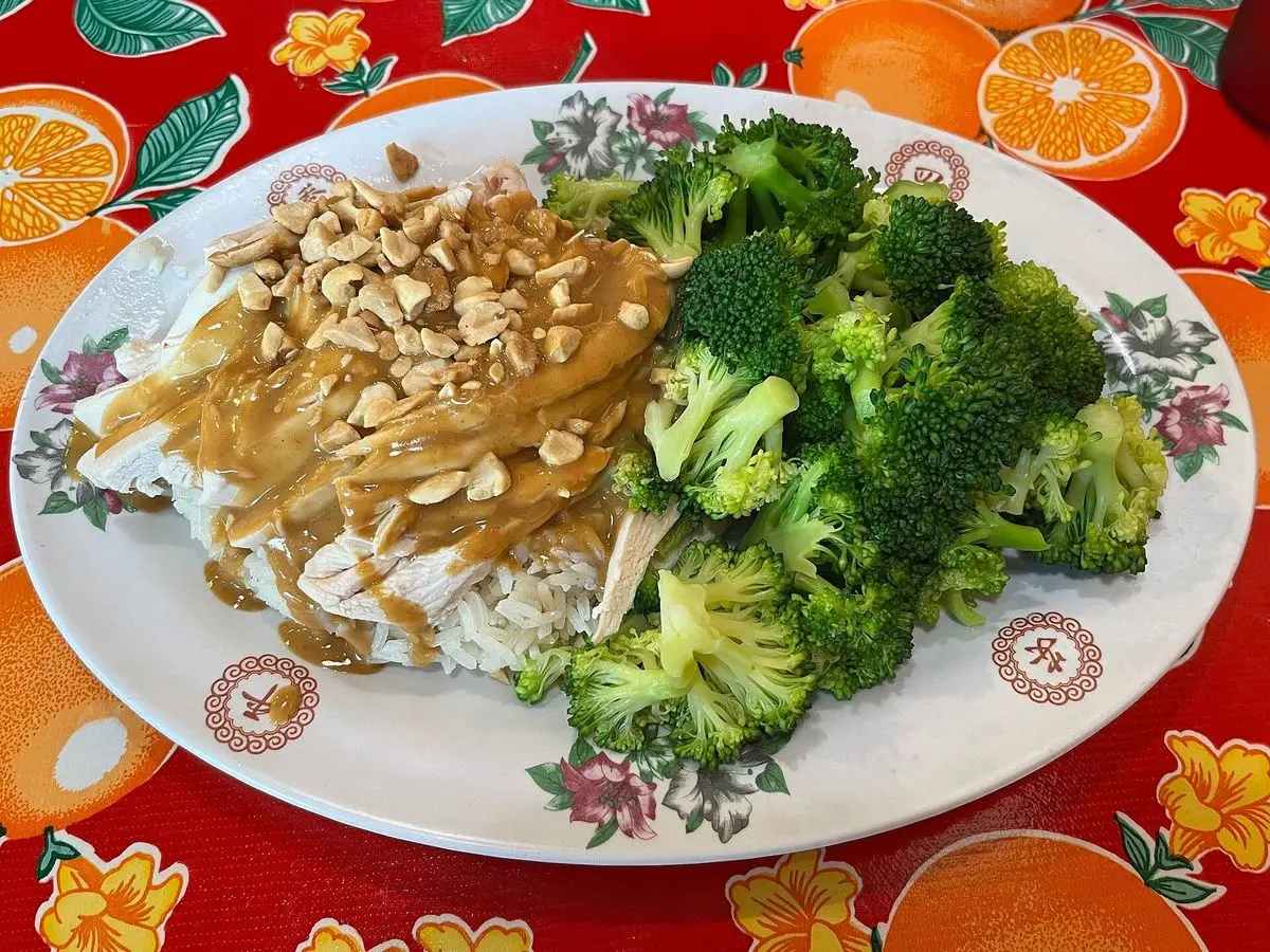 Plato de arroz con pollo cubierto de salsa de cacahuete, cacahuetes picados y brócoli