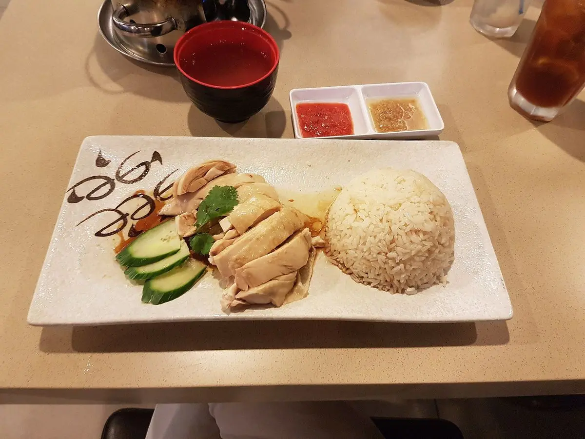 Pollo hervido troceado con arroz blanco y rodajas de pepino en una bandeja blanca