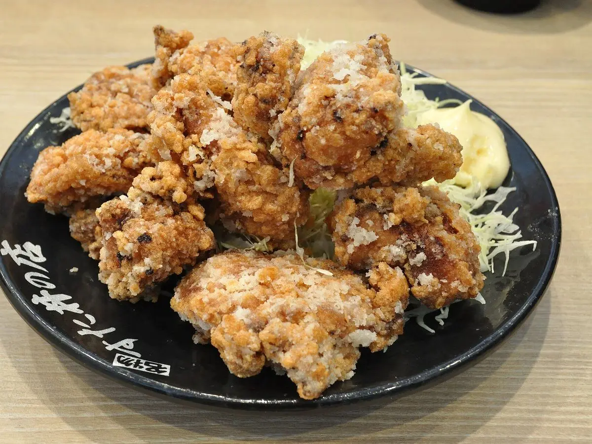 Trozos de pollo frito karaage con col rallada y mayonesa en un plato negro