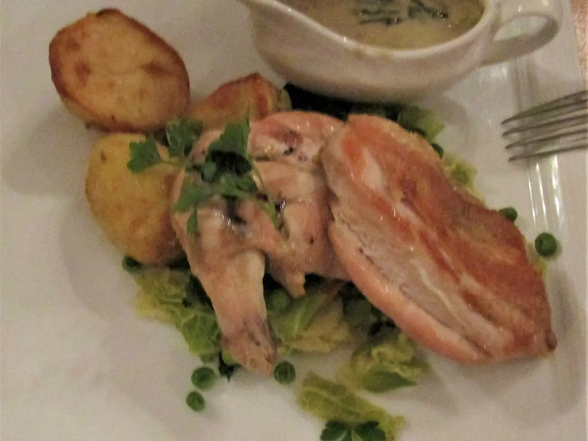 Pechuga de pollo laminada con patatas asadas, guisantes y salsa cremosa en una salsera