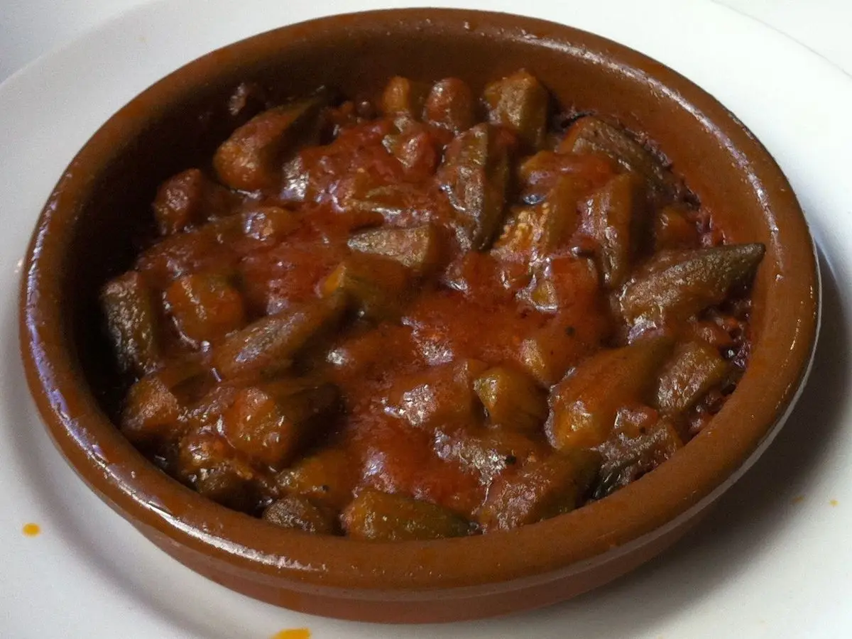 Cazuela de barro con guiso de okra y carne en salsa de tomate roja