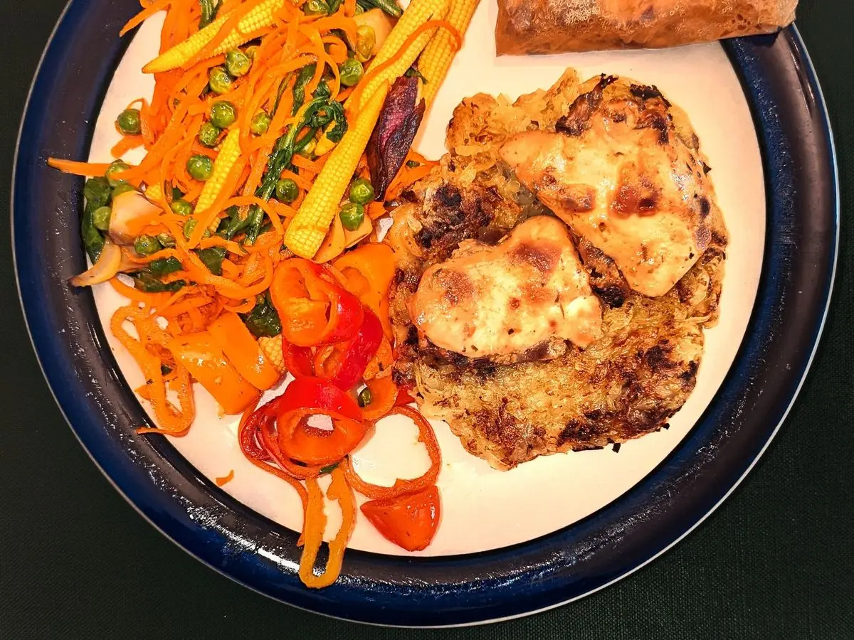 Plato con pechuga de pollo gratinada, zanahoria, pimiento en tiras y rollito de papillote