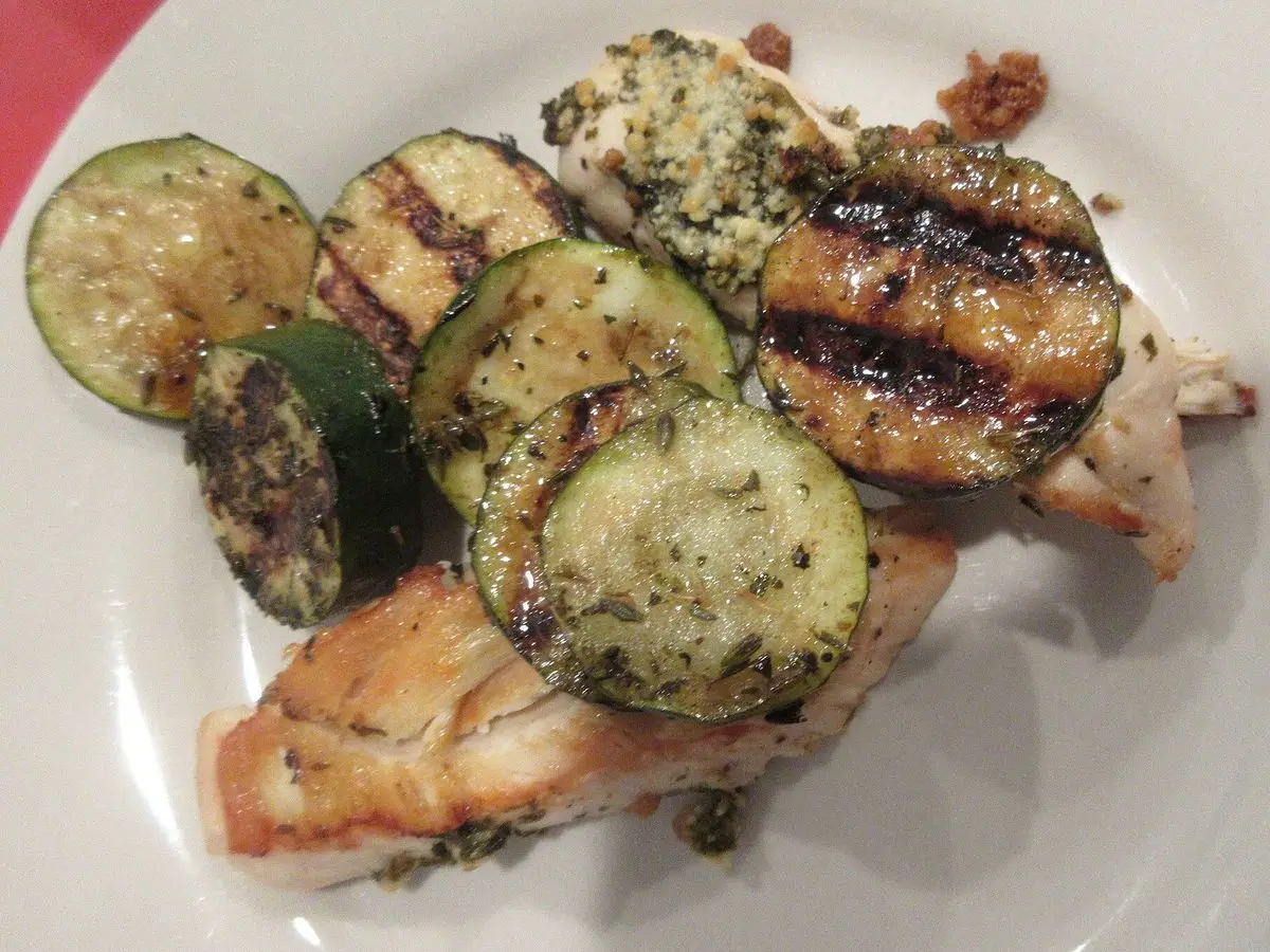 Pechuga de pollo a la plancha con rodajas de calabacín asado en un plato blanco
