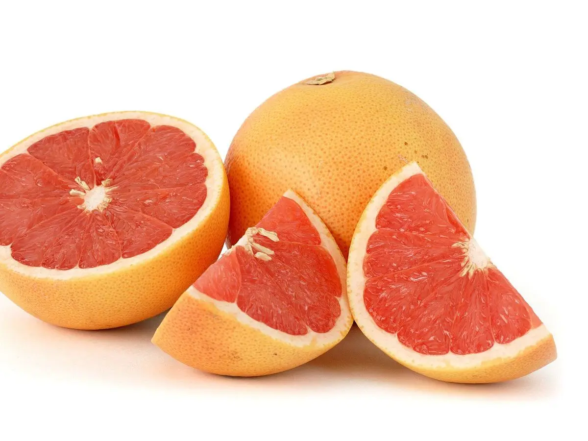 Pomelos rosados enteros, partidos y en gajos sobre fondo blanco