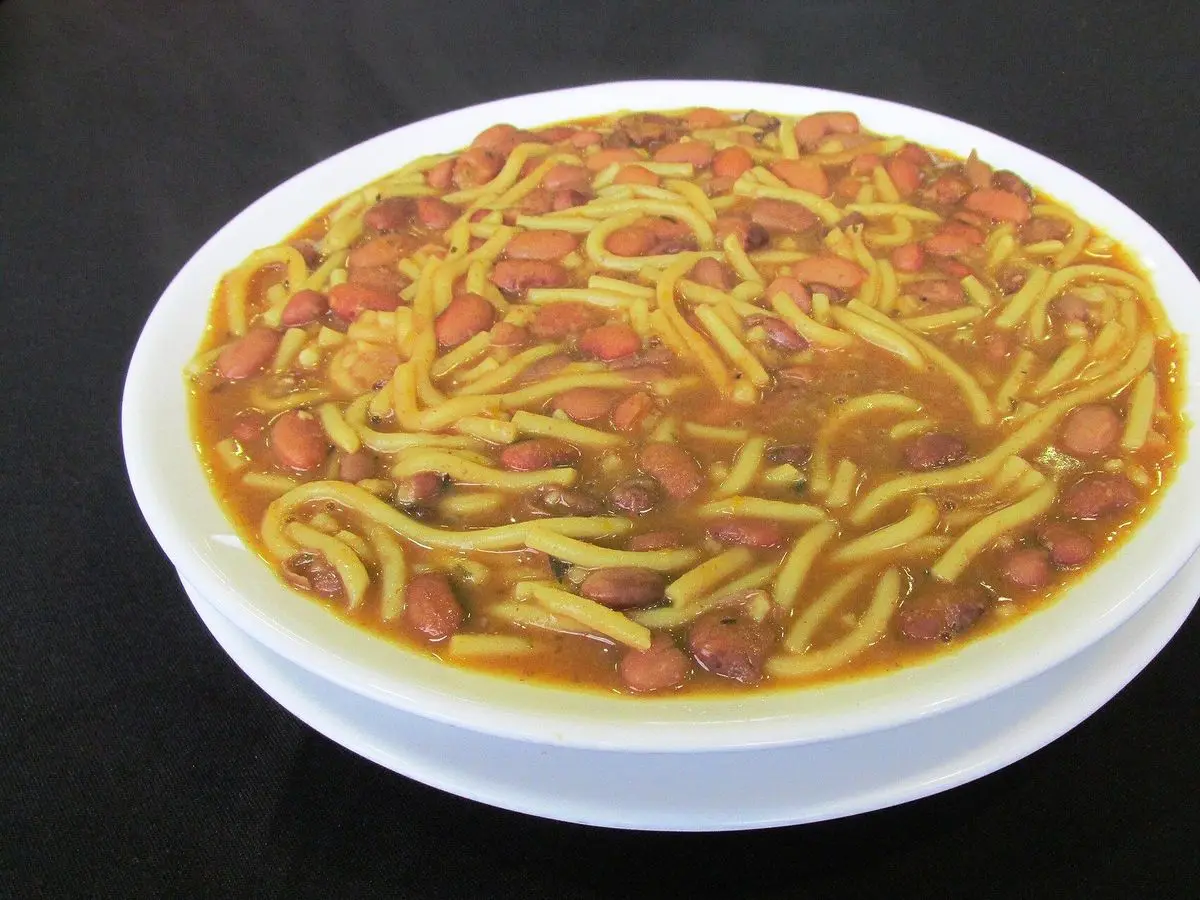 Fuente blanca de porotos guisados con tallarines amarillos