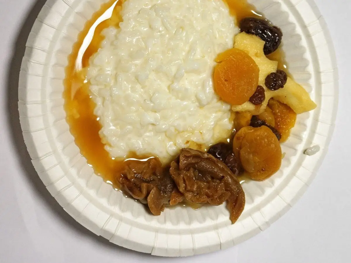 Plato de porridge cremoso con fruta seca y almíbar dorado sobre un plato de papel