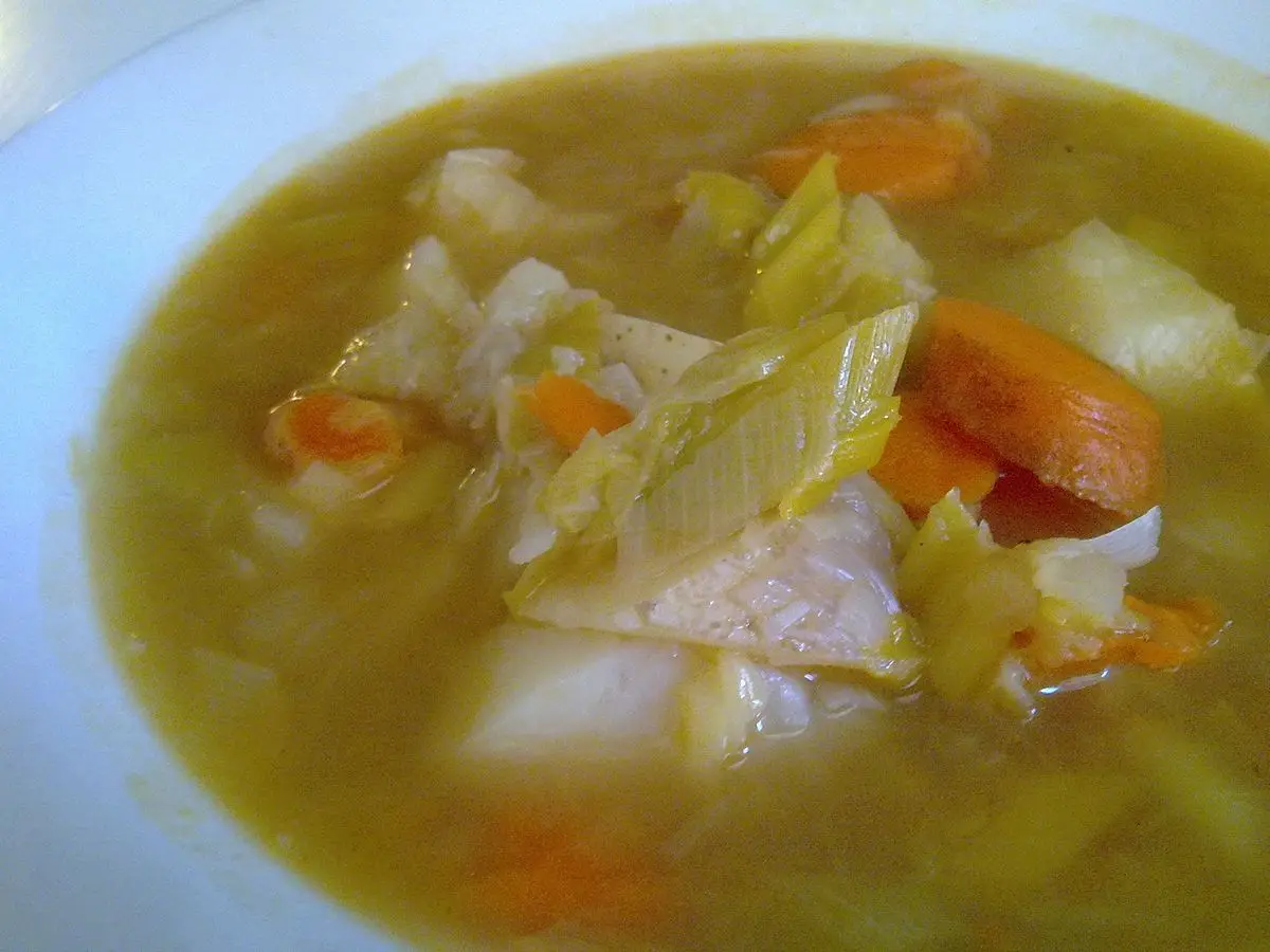 Plato hondo de sopa de puerro, col, patata y zanahoria en caldo claro