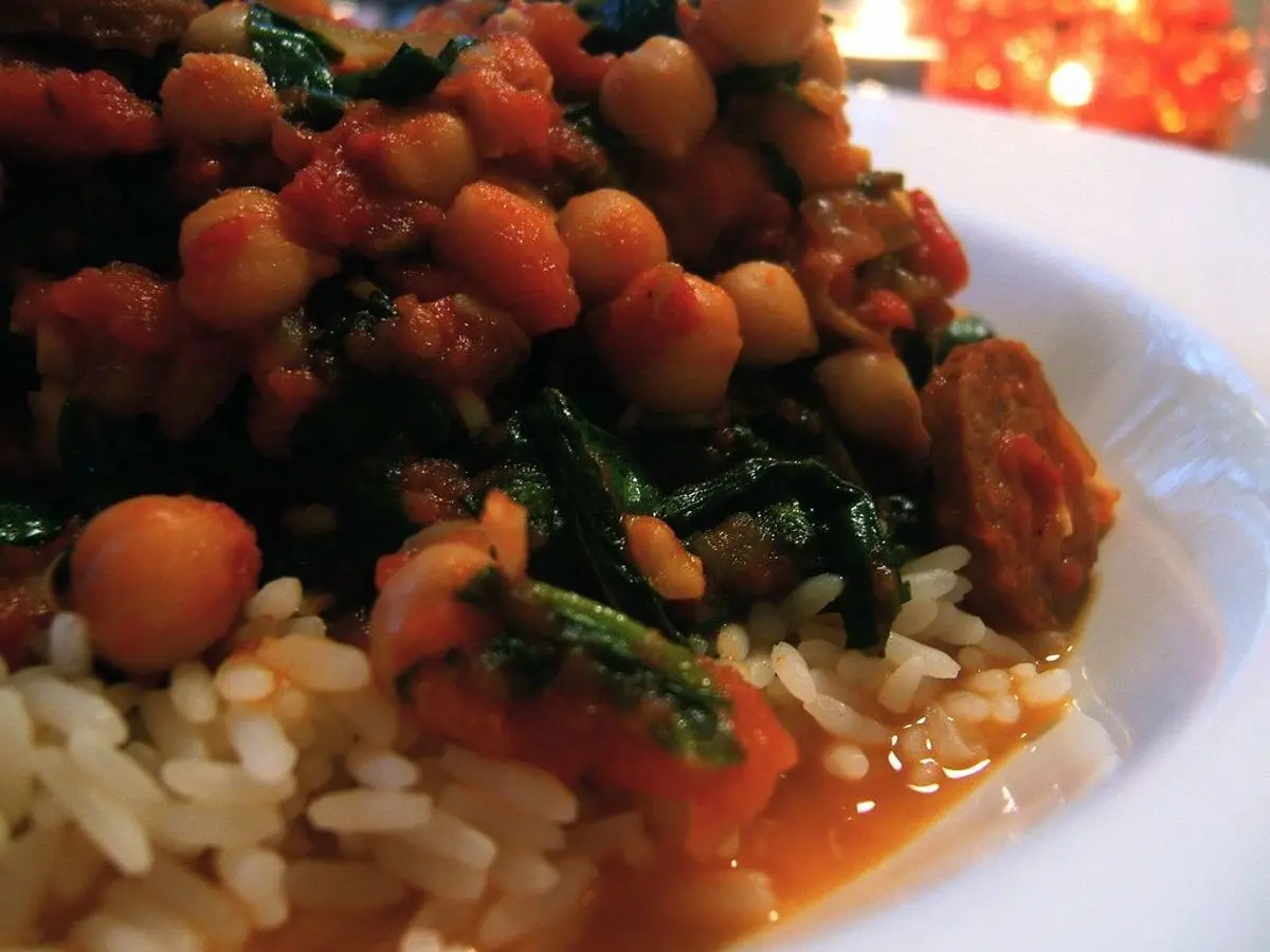 Guiso de garbanzos con chorizo y espinacas sobre arroz blanco en un plato