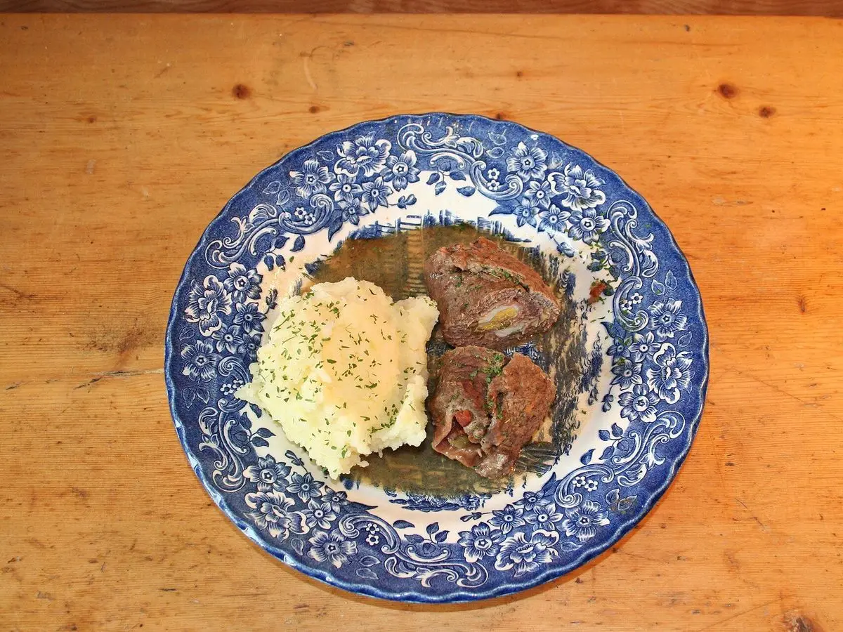 Filete de carne en salsa con huevo revuelto sobre un plato azul y blanco