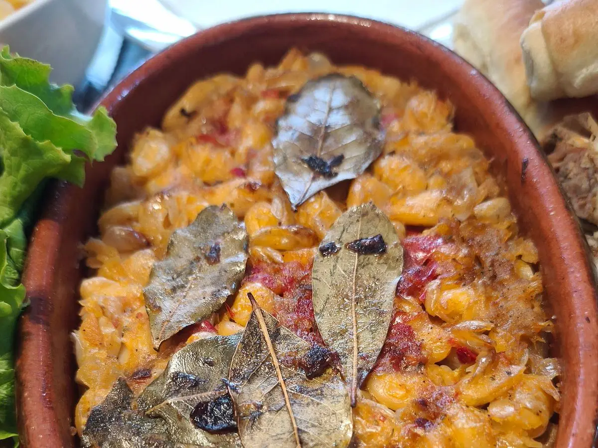 Cazuela de barro con alubias blancas al horno con hojas de laurel