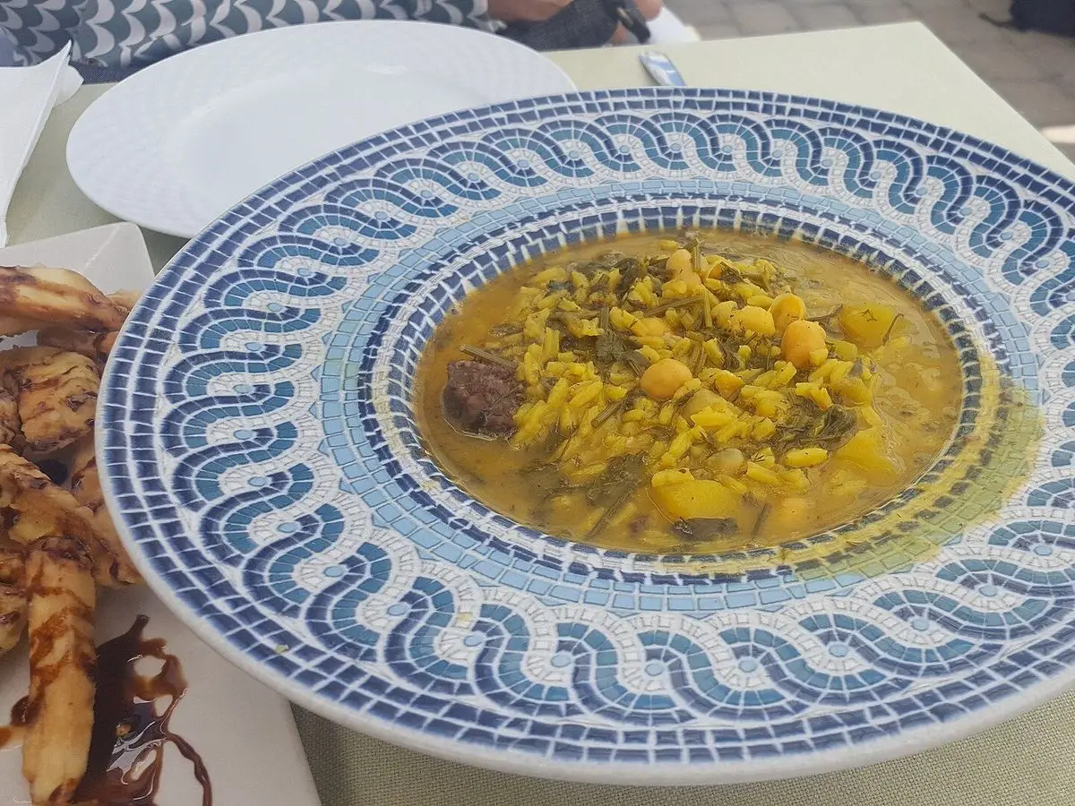 Plato hondo de cerámica azul con puchero de hinojos, alubias, patata y morcilla
