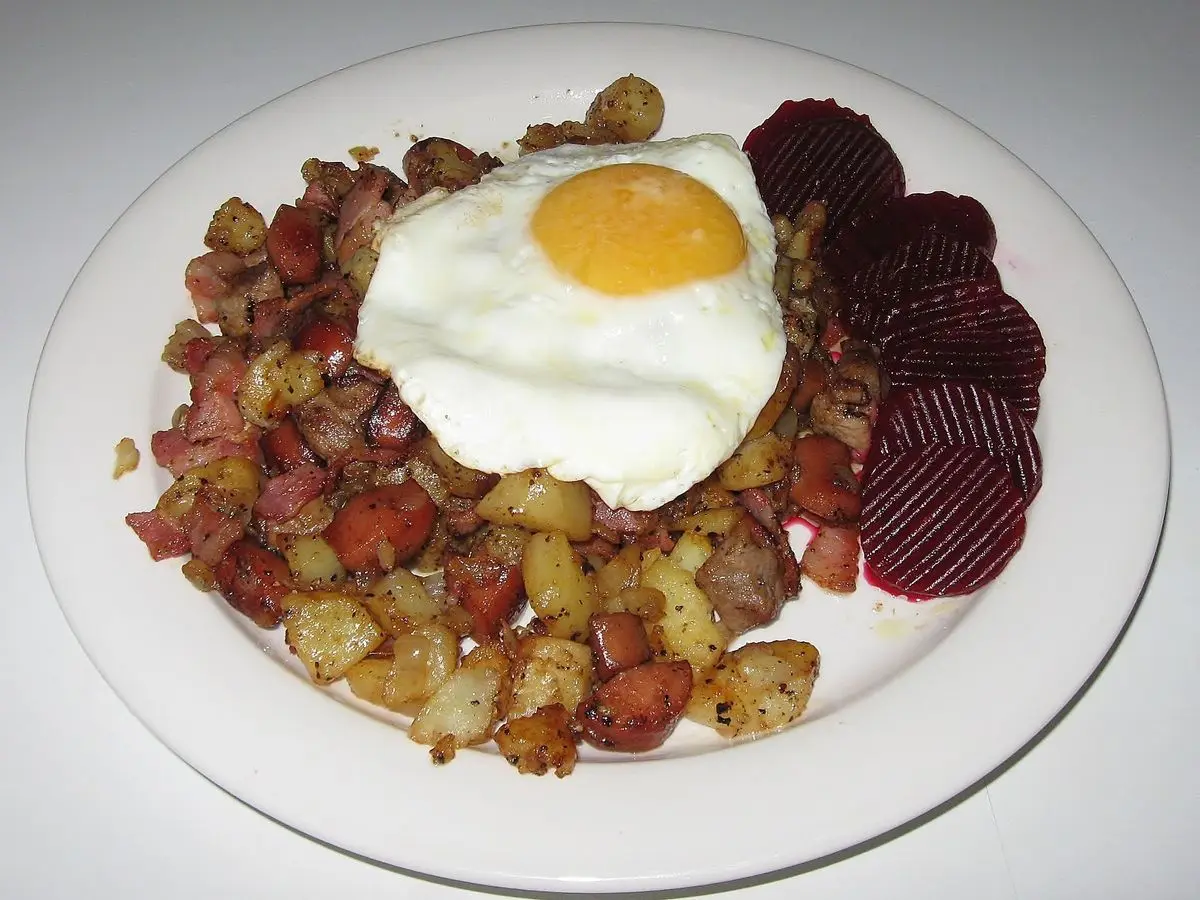 Pytt i panna de patata y carne en dados con huevo frito y rodajas de remolacha en un plato blanco