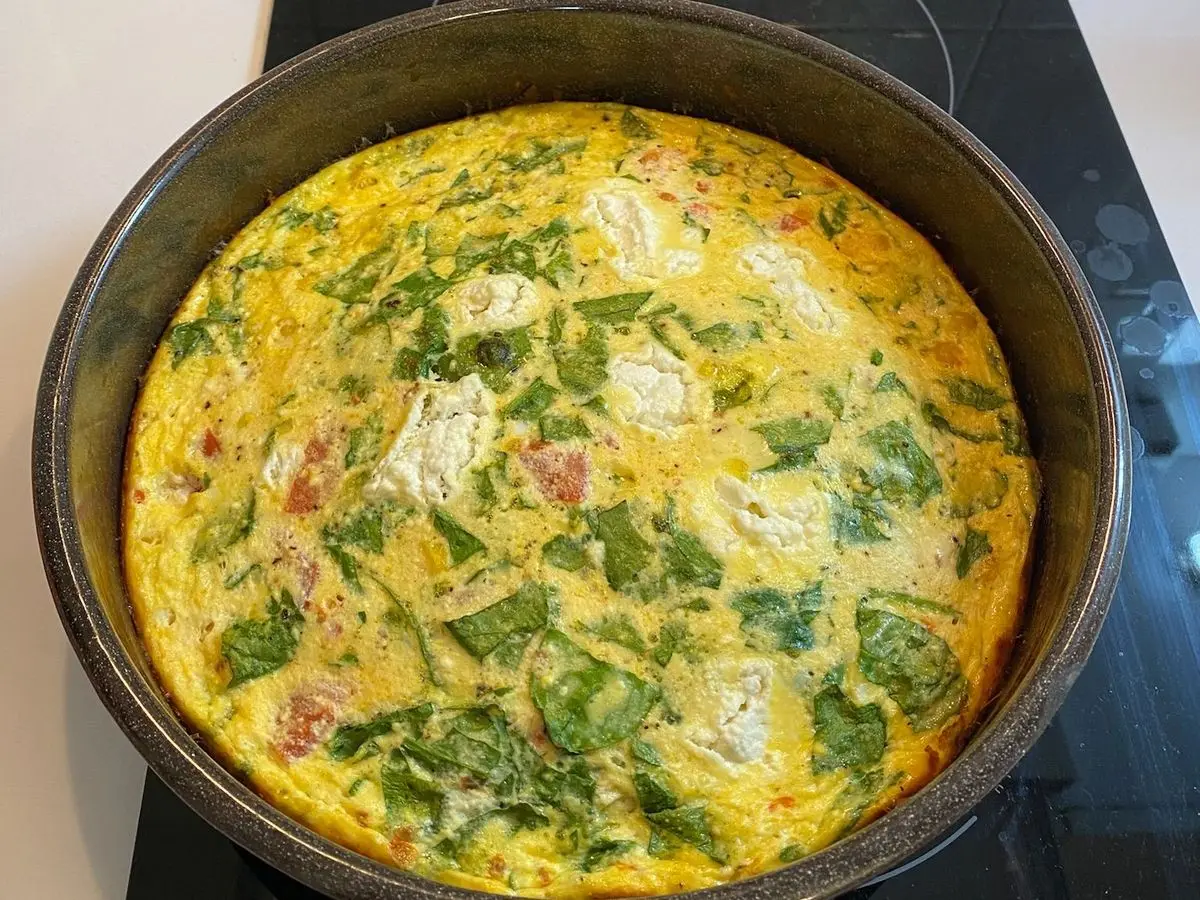 Molde con un gratinado de huevo, espinacas y trozos de queso blanco recién horneado