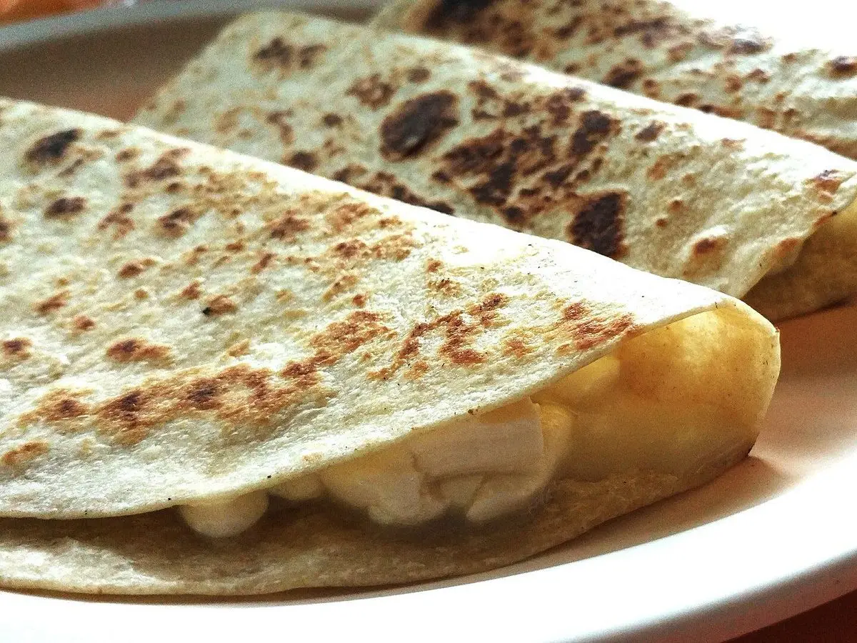 Quesadillas de tortilla doradas rellenas de plátano en rodajas sobre un plato blanco
