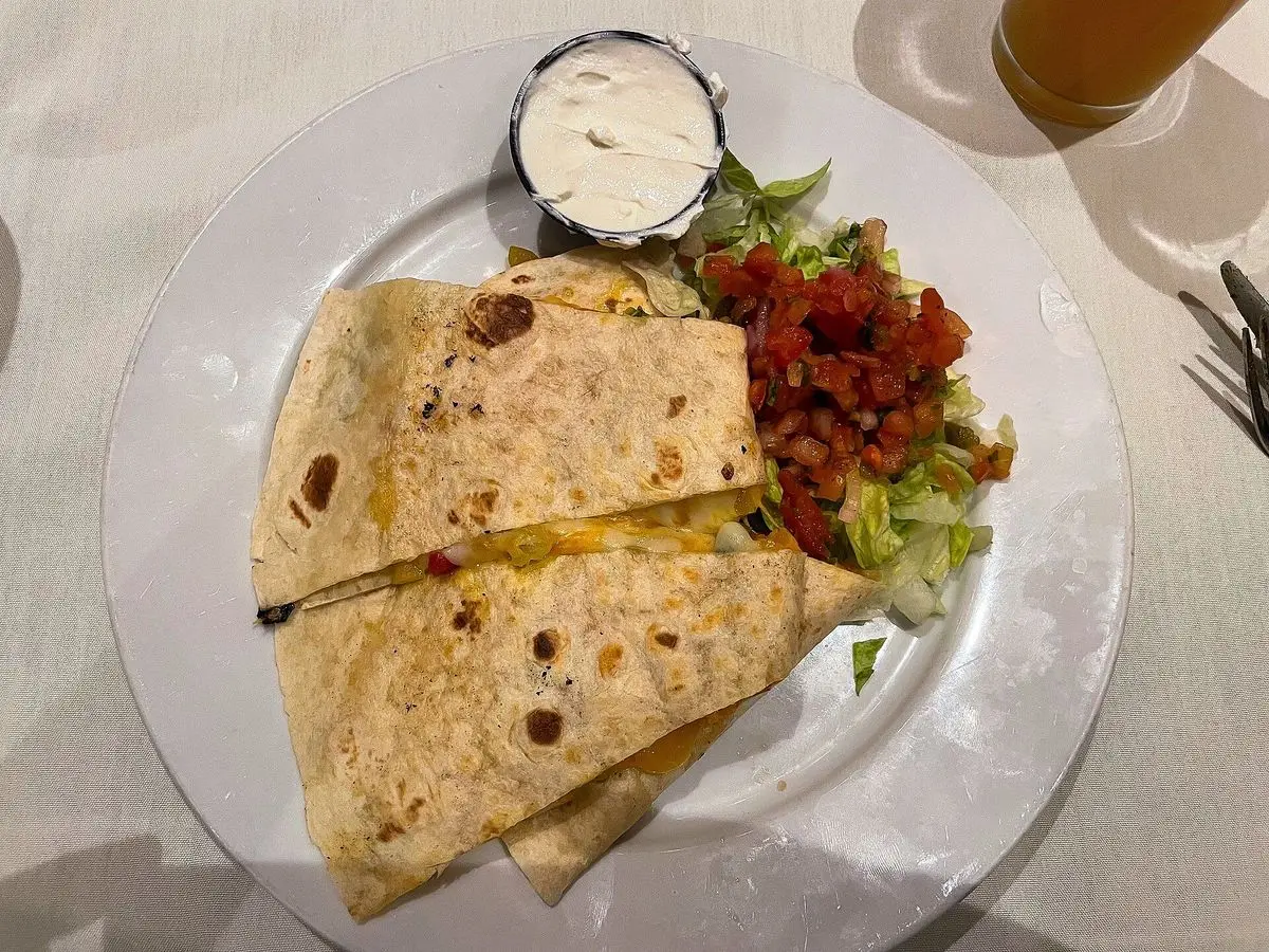 Quesadillas de tortilla cortadas en triángulos con ensalada y salsa en un plato blanco