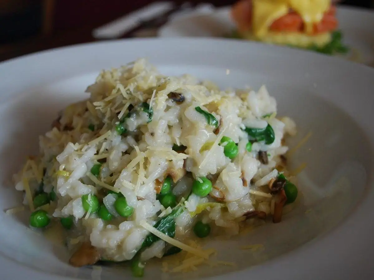 Plato de arroz cremoso tipo risotto con guisantes y queso rallado por encima