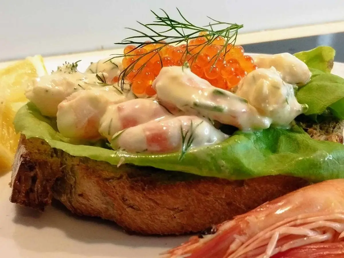 Tosta de pan oscuro con lechuga, gambas peladas en salsa cremosa, huevas naranjas y eneldo