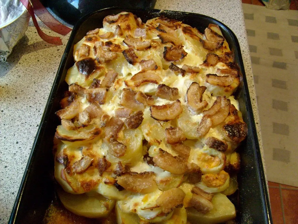 Fuente de horno con patata gratinada en capas con huevo y embutido