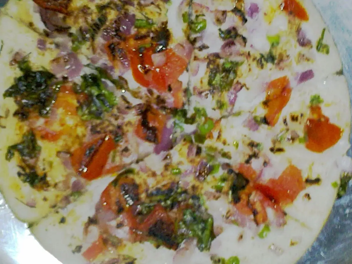 Uttapam, torta india gruesa cubierta de tomate, cebolla y cilantro picados