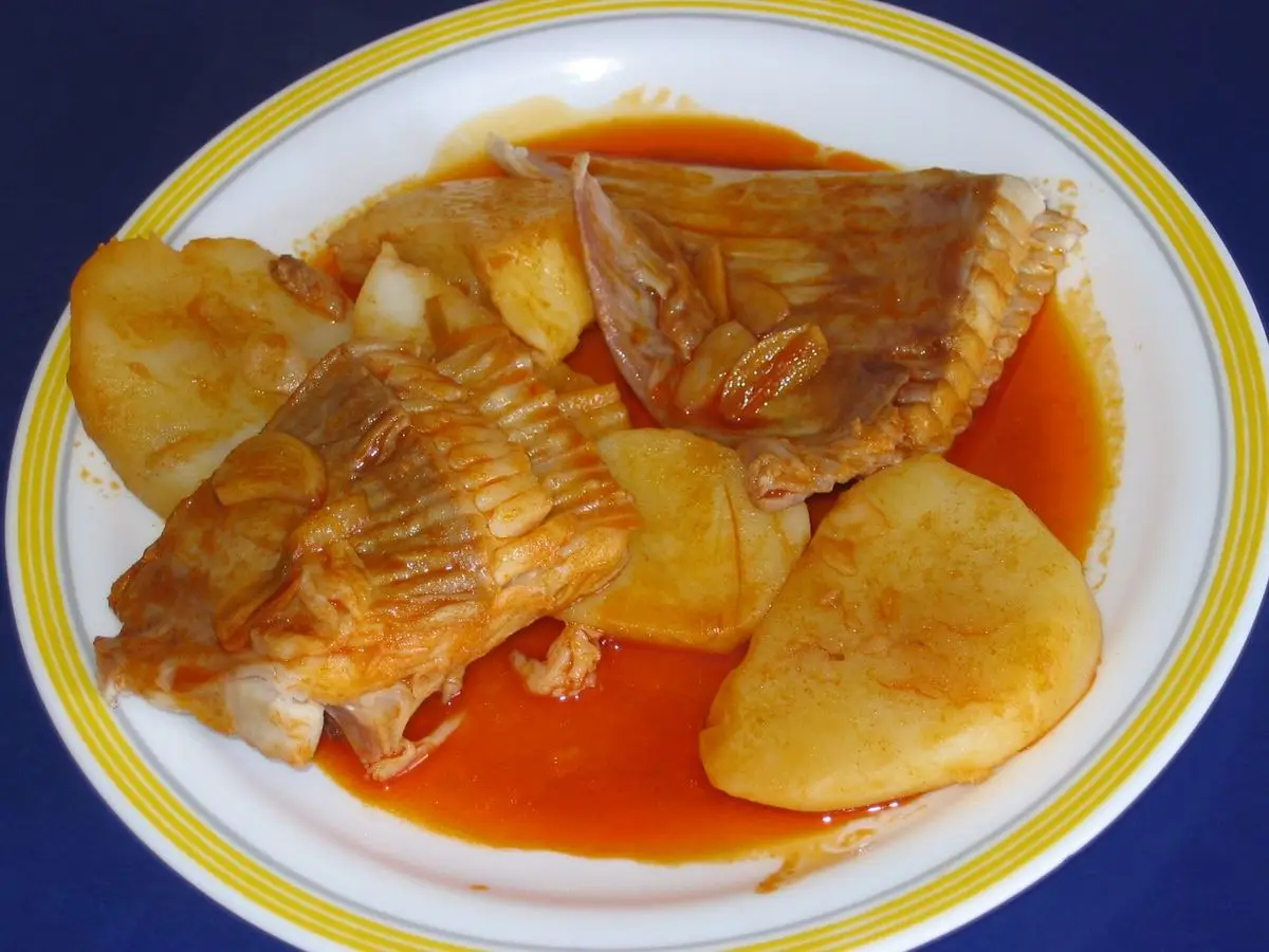 Plato de aletas de raya con patatas cocidas en salsa roja de pimentón y aceite
