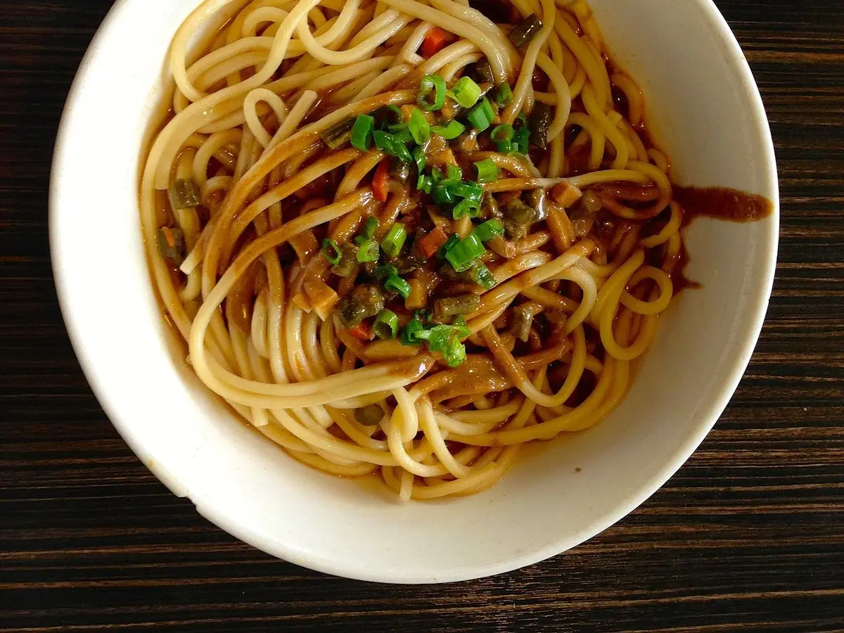 Cuenco blanco de fideos de trigo con salsa y cebolleta picada, re gan mian de Wuhan