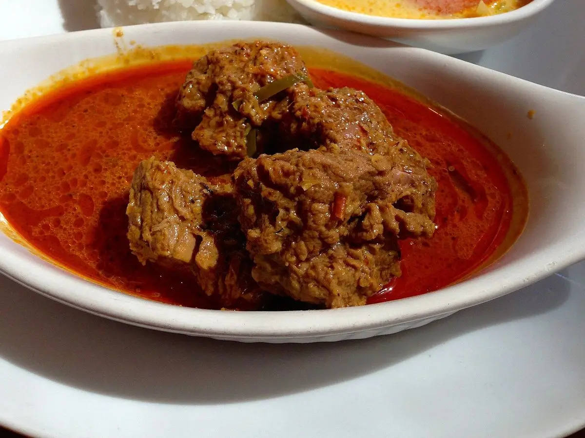 Rendang de ternera en salsa roja con arroz blanco y un cuenco de verduras al curry