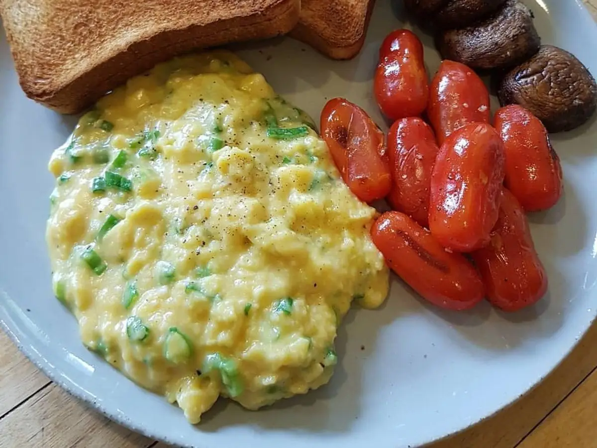 Plato con huevos revueltos, setas asadas, tomates cherry y tostadas integrales