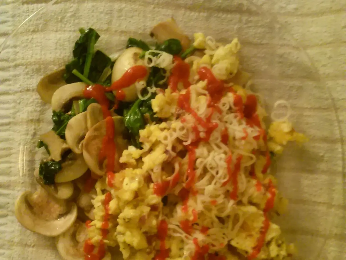 Revuelto de huevo con champiñones laminados y espinacas en un plato