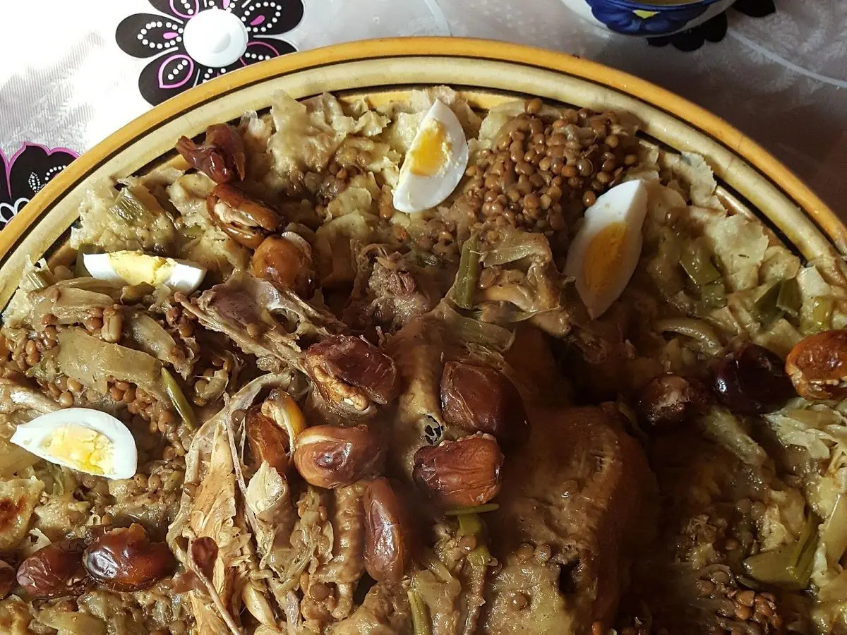 Fuente de rfissa con pollo sobre pan desmigado, lentejas, dátiles y huevos duros