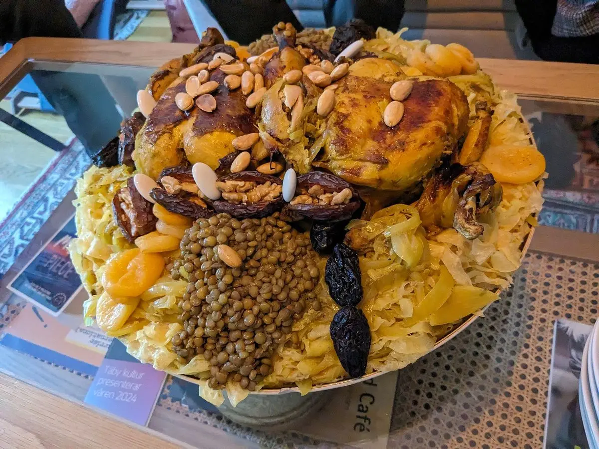 Fuente grande de rfissa con pollo, lentejas, almendras y ciruelas sobre tiras de pan en caldo especiado