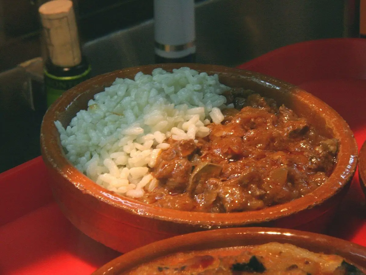 Cazuela de barro con riñones guisados en salsa junto a arroz blanco