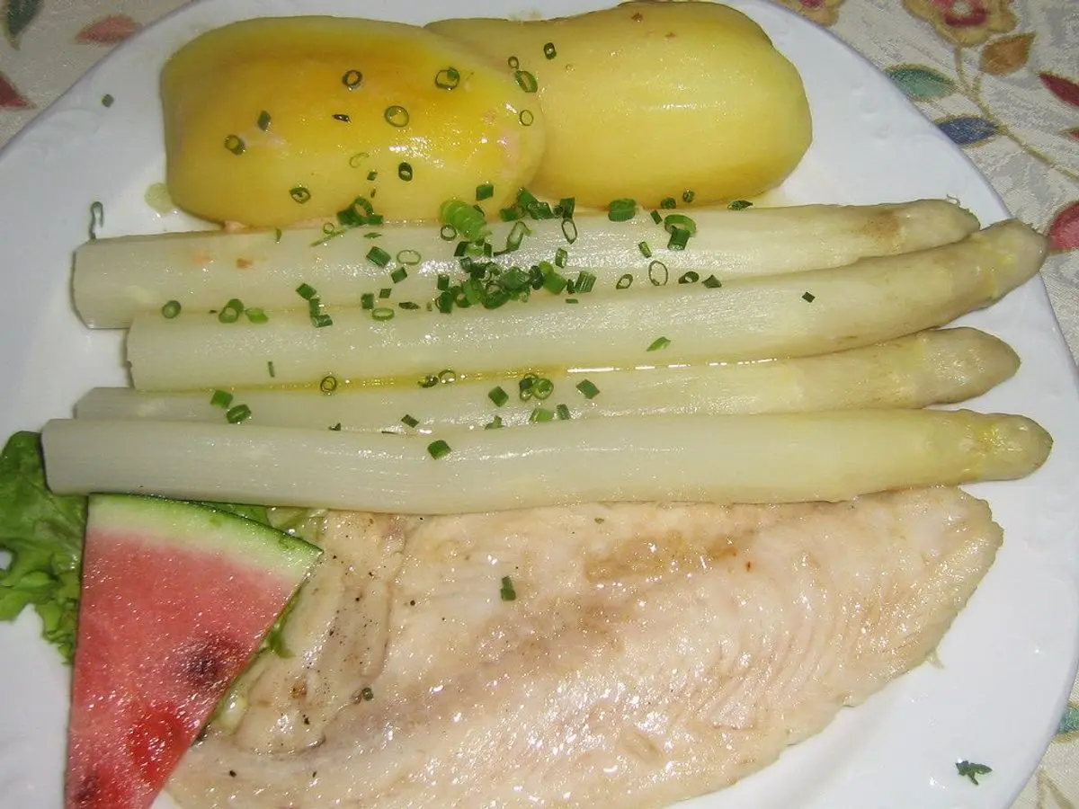 Filete de pescado blanco al vapor con espárragos blancos, patatas cocidas y una cuña de melón