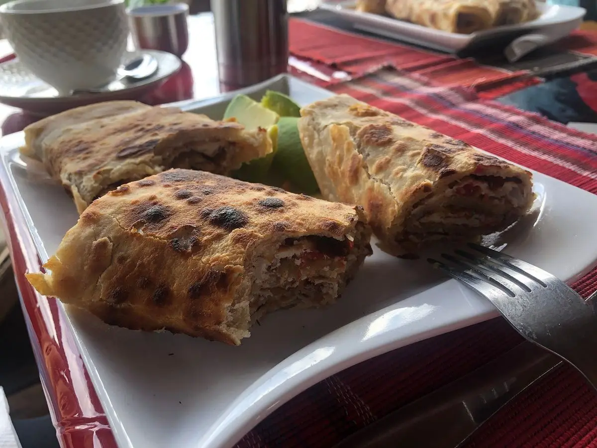 Rollos de chapati rellenos servidos en un plato blanco junto a lechuga