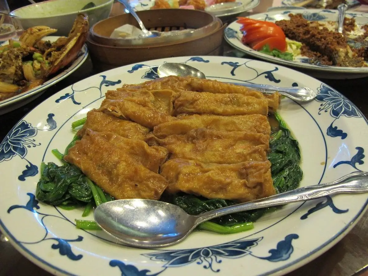 Filete de pescado dorado sobre un lecho de espinacas en un plato de porcelana azul y blanca