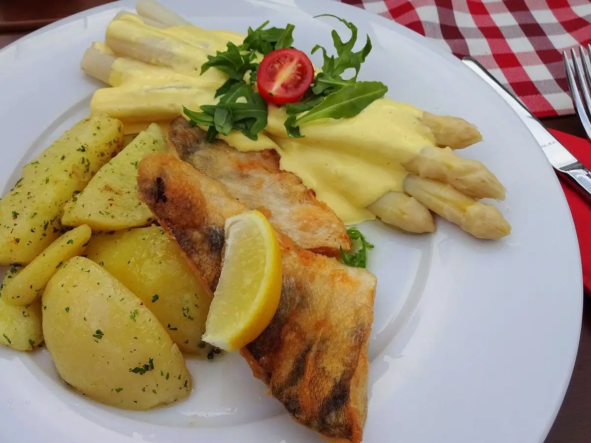 Filetes de pescado blanco con patatas hervidas, espárragos blancos, salsa cremosa y una rodaja de limón