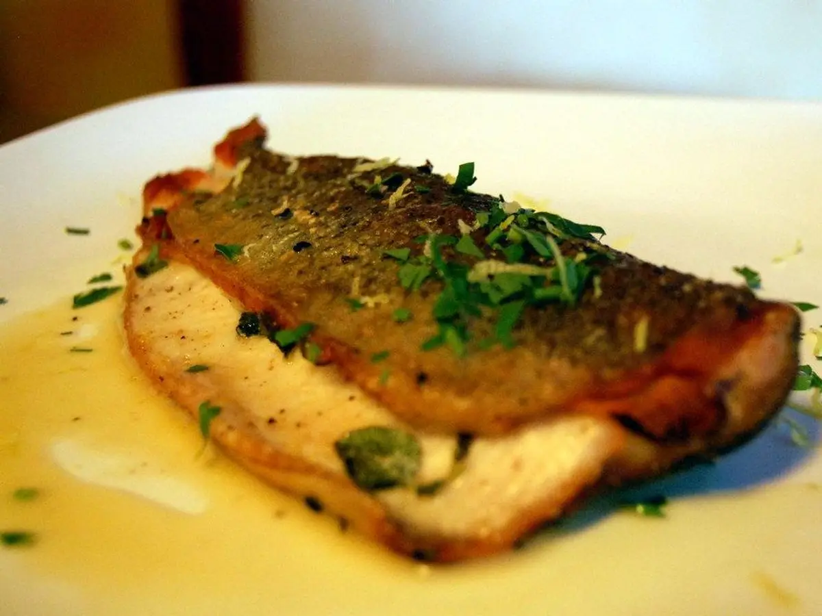Filetes de pescado doblados con jamón curado y hojas de salvia, en salsa de mantequilla con perejil
