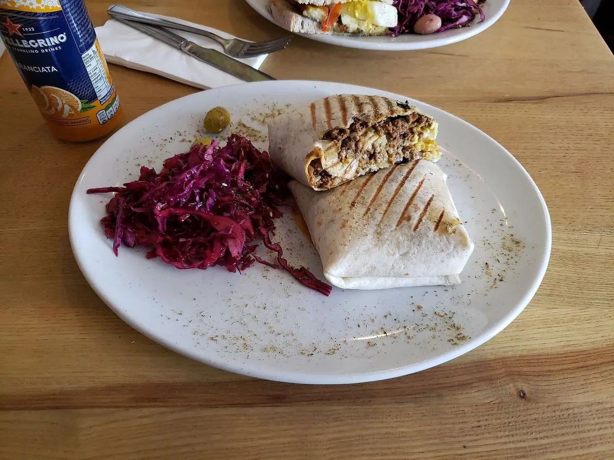 Rollito de tortilla relleno cortado sobre un plato blanco junto a ensalada de lombarda