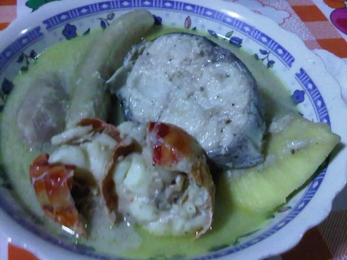 Plato hondo de guiso caribeño de pescado en salsa de coco con plátano verde y dumpling