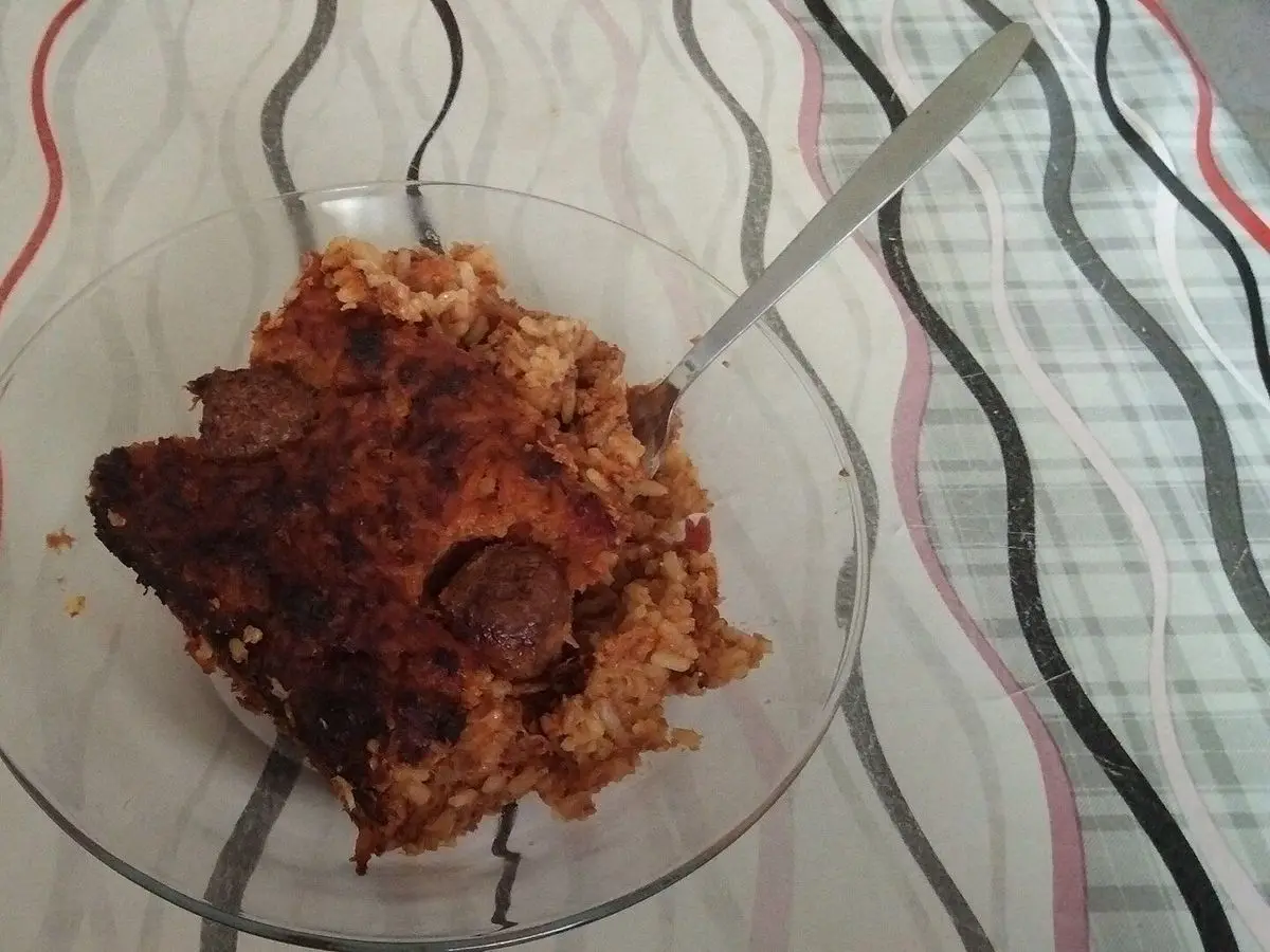 Ración de arroz al horno con carne y tomate gratinado en un plato de cristal