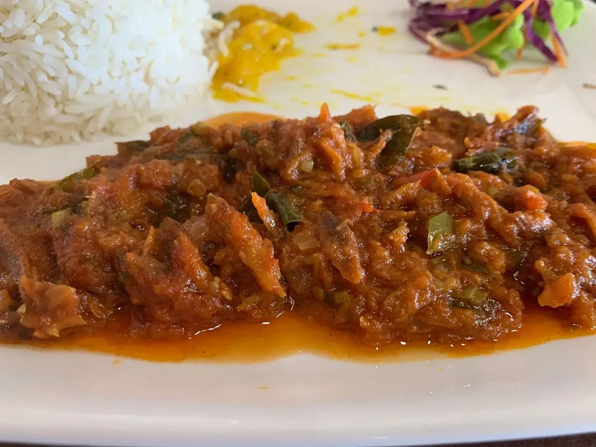 Pescado en salsa criolla de tomate rojo servido con arroz blanco en un plato