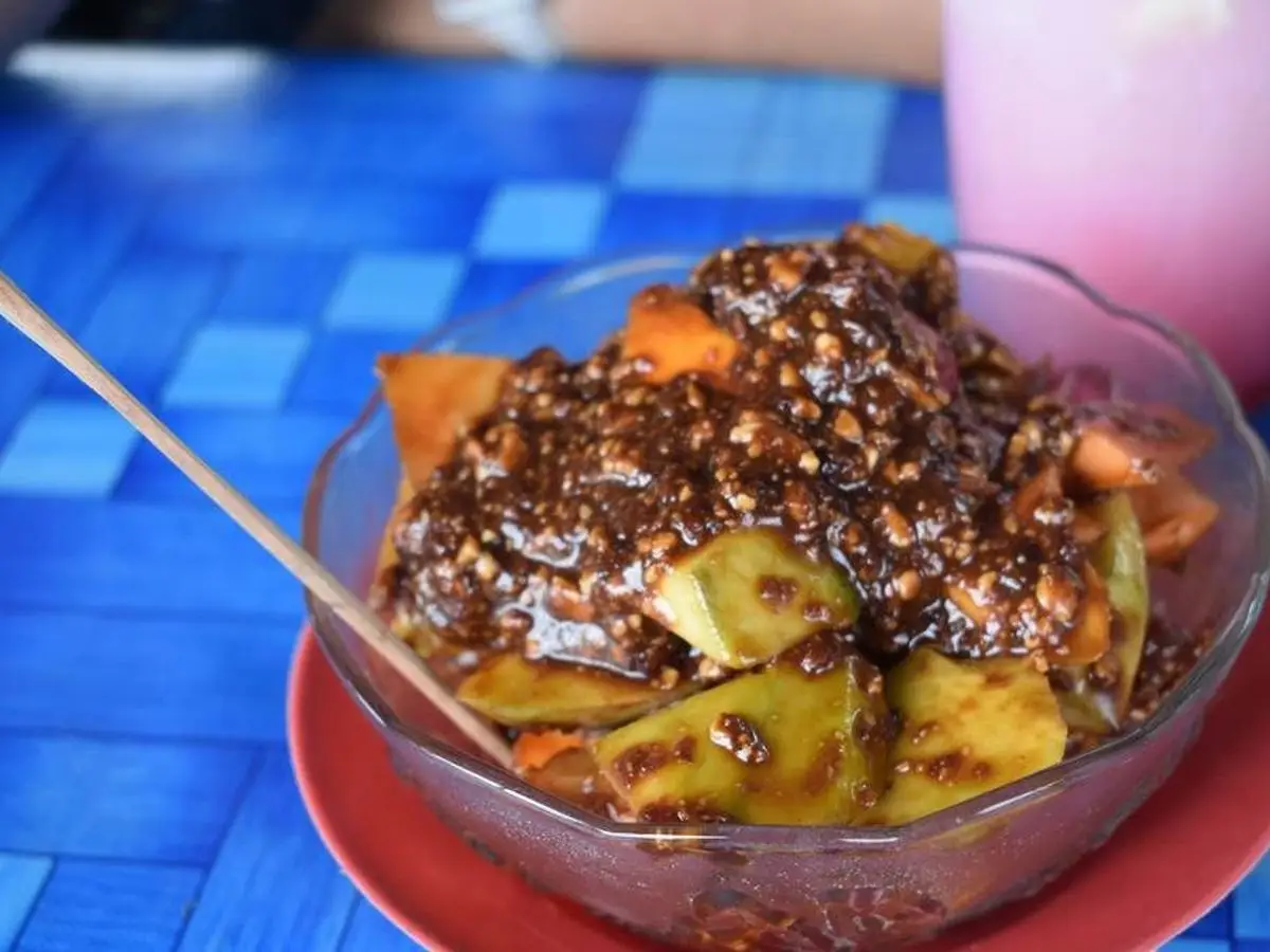 Cuenco de cristal con rujak, fruta troceada con salsa oscura de tamarindo y cacahuete