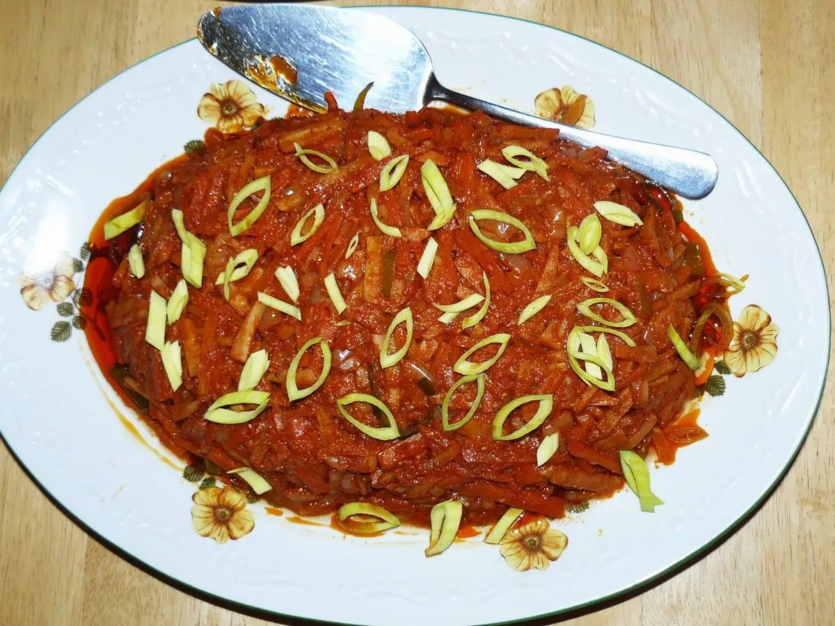 Fuente ovalada de pescado con verduras en salsa de tomate, con aros de puerro por encima