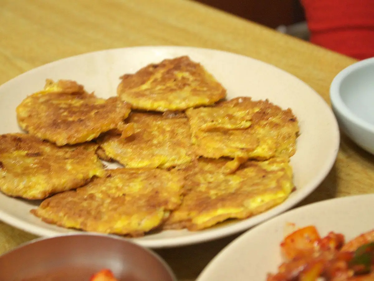 Plato con tortitas de pescado rebozadas en huevo doradas, con kimchi al lado