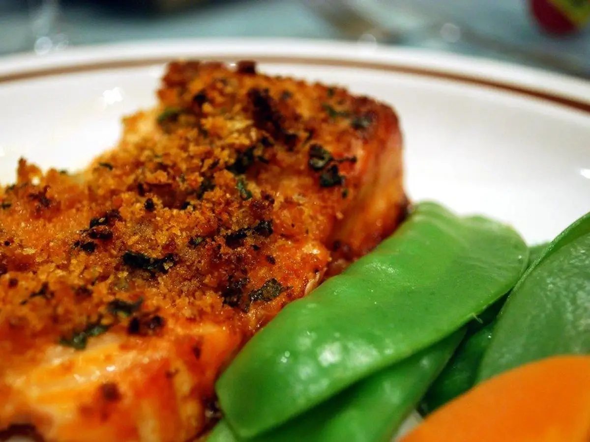 Filete de salmón con costra dorada de frutos secos y hierbas, con guisantes tirabeques y zanahoria