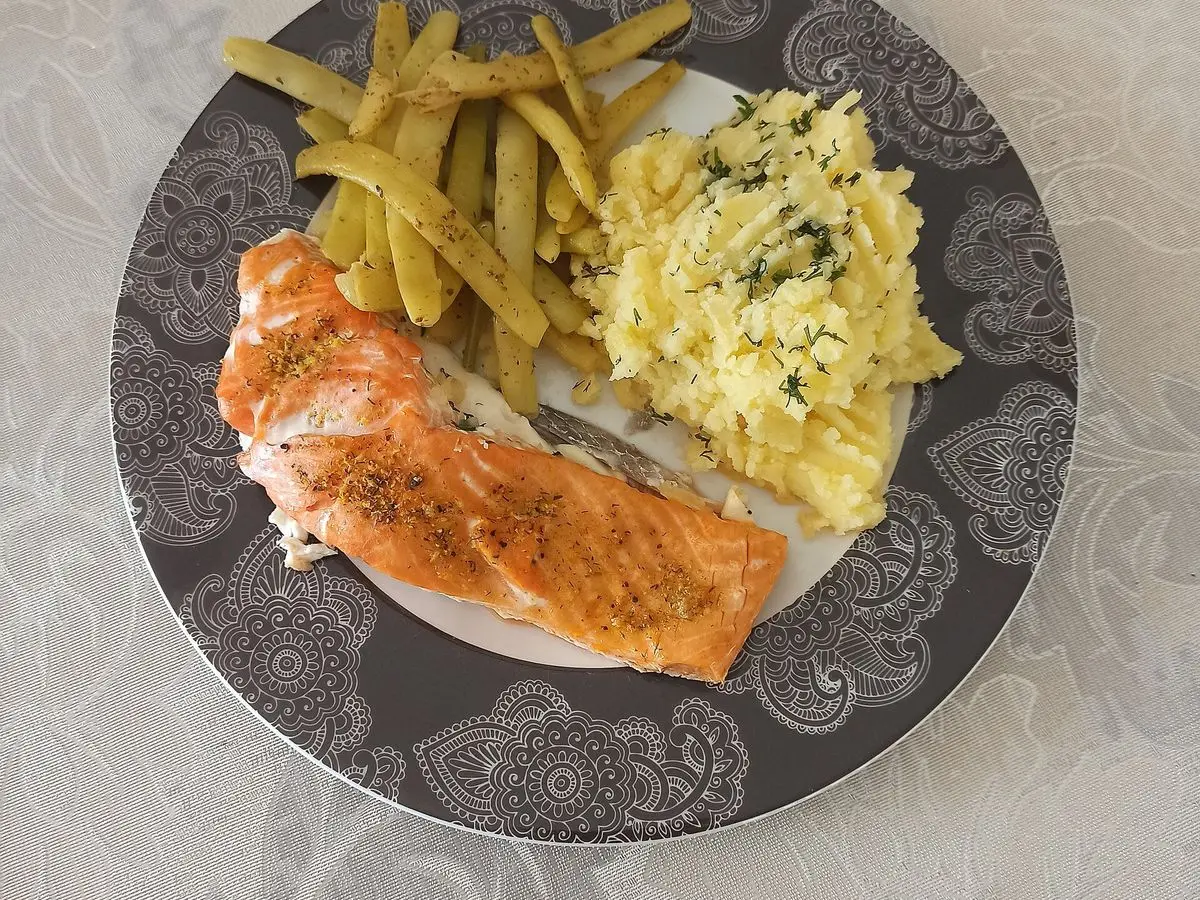 Filete de salmón al horno con judías verdes y puré de patata en un plato gris